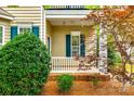 Charming covered front porch with white railings and teal shutters, framed by lush foliage at 10407 Alvarado Way, Charlotte, NC 28277