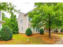 Side exterior view of a home with light siding, green shutters, and mature landscaping at 10407 Alvarado Way, Charlotte, NC 28277