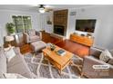 A modern living room featuring wood floors, a brick fireplace, and comfortable seating with neutral decor at 10518 Fairway Ridge Rd, Charlotte, NC 28277