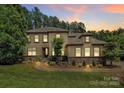 Stunning two-story home with manicured lawn, mature trees, and elegant stone accents at twilight at 11052 Preservation Park Dr, Charlotte, NC 28214