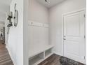Bright entryway with modern coat rack and bench, leading to hardwood floors and stylish decor at 15023 Longmoore Dr, Charlotte, NC 28278
