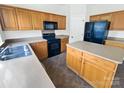 This kitchen features wood cabinets, black appliances and a kitchen island at 18414 Victoria Bay Dr, Cornelius, NC 28031