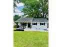 A beautifully renovated white ranch-style home with dark shutters and trim, plus a covered front porch at 330 Willow Oak Cir, Lancaster, SC 29720