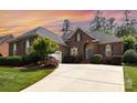 Brick home with a curved driveway, beautiful landscaping, and an attached garage creates a welcoming entrance at 4409 Winder Trl, Gastonia, NC 28056