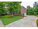 Brick home boasts a circular driveway, three-car garage, and lush landscaping at 5004 Woodview Ln, Matthews, NC 28104