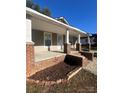 Inviting covered front porch with brick columns and landscaped flower beds, perfect for relaxing at 524 Railroad Nw Dr, Concord, NC 28025