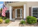 Inviting front porch with brick accents, a security system sign, and landscaping with decorative rock features at 9593 Indian Beech Nw Ave, Concord, NC 28027