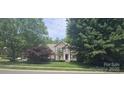 Attractive two-story brick home with a well-maintained lawn and mature trees providing shade at 15494 Donnington Dr, Charlotte, NC 28277