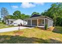 Charming gray home featuring a cozy front porch and an expansive driveway at 251 Hall Nw Ave, Concord, NC 28027
