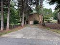 Long concrete driveway leads to a brick home with an attached garage surrounded by mature trees at 5198 Wright Dr, Hickory, NC 28602