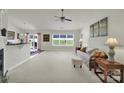 Open-concept living room with neutral carpet, a ceiling fan, and natural light from the backyard view at 6192 Kilchurn Dr, Fort Mill, SC 29707