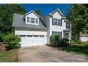 View of a two-story white home featuring an attached two-car garage and well-kept landscaping at 8619 New Oak Ln, Huntersville, NC 28078