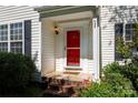 Close-up of a bright red front door with brick steps and manicured landscaping at 8619 New Oak Ln, Huntersville, NC 28078