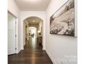 Hallway with dark hardwood floors and white walls, arched doorway leading into another room, and a piece of artwork on the wall at 10112 Andres Duany Dr, Huntersville, NC 28078