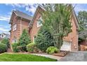 Brick home featuring an attached garage and beautifully landscaped yard with mature trees and shrubs at 103 Samuel Guilford Ct, Charlotte, NC 28270