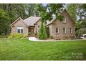 Attractive brick home with manicured lawn, mature trees, and a welcoming walkway at 12900 Westmoreland Rd, Huntersville, NC 28078