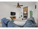 The living room boasts a stone fireplace, a ceiling fan, and a comfortable blue sectional sofa at 12900 Westmoreland Rd, Huntersville, NC 28078