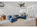 A bright living room features a blue sectional sofa, high ceilings, and views into the entryway at 12900 Westmoreland Rd, Huntersville, NC 28078