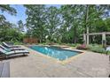 A private pool with a hot tub surrounded by greenery and lounge chairs on a stone patio at 12900 Westmoreland Rd, Huntersville, NC 28078