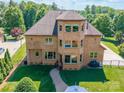 Aerial shot of a brick home with a backyard, a paver patio, and well-manicured lawn surrounded by trees at 13056 Long Common Pkwy, Huntersville, NC 28078
