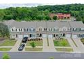 An aerial view displays a row of townhomes with well-manicured lawns, driveways, and green tree line in the distance at 16039 Simril Ct, Charlotte, NC 28278