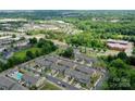 An aerial view of townhomes surrounded by lush greenery, roads, and commercial buildings within the neighborhood at 16039 Simril Ct, Charlotte, NC 28278