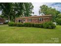 Traditional one-story brick home with manicured lawn and mature trees, set against a blue sky backdrop at 3424 Autumn Dr, Gastonia, NC 28056