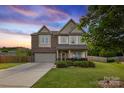 Charming two-story home with a manicured lawn, a two-car garage, and a combination of brick and siding at 4430 Bravery Sw Pl, Concord, NC 28027