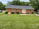 Exterior of a brick house featuring a well-manicured lawn and a concrete patio at 5734 Brookhaven Rd, Charlotte, NC 28210
