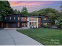 Striking modern home with a concrete driveway and well-manicured front lawn at sunset at 5925 Creola Rd, Charlotte, NC 28270