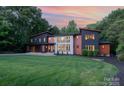 Striking modern home with unique architectural details and a well-manicured front lawn at sunset at 5925 Creola Rd, Charlotte, NC 28270