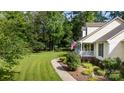 Side yard view featuring lush trees, green grass, landscaping, and a charming home with a welcoming front porch at 785 Sanside Dr, York, SC 29745