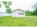 View of the detached garage with a white fence, surrounded by a grassy lawn at 800 Charles Rd, Shelby, NC 28150