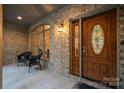 Covered front porch with brick walls, an arched window, and a wooden front door with stained glass at 9002 Fair Oak Dr, Sherrills Ford, NC 28673