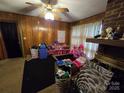 Comfortable living room featuring classic wood paneling, a brick fireplace and a vintage ceiling fan at 116 E Graves St, Candor, NC 27229