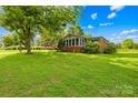 Landscaped front yard with lush green lawn and mature trees surrounding this charming brick home at 119 Oak Ave, Shelby, NC 28152