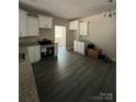 An open kitchen showcases bright cabinets, granite counters, and dark gray wood-look flooring at 1987 Robert Rufty Ln, Catawba, NC 28609