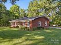 Side view of a brick home with lush green lawn and mature trees, offering a serene setting at 2216 Griffith Rd, Monroe, NC 28112