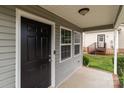 Inviting front porch featuring a black front door, gray siding, and a glimpse of the backyard at 252 Sweet Bay Nw Ln, Concord, NC 28027