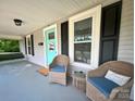 Inviting front porch featuring wicker chairs with blue cushions and a charming teal door with decorative accents at 329 Highland Dr, Lincolnton, NC 28092