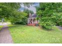 Beautiful side yard view of a brick home with lush greenery and a porch at 411 Hanna St, Gastonia, NC 28052