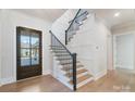 Bright foyer featuring a modern staircase with a black railing and wood steps and wood floors at 7215 Alexander Rd # 4, Charlotte, NC 28270