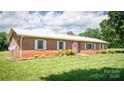 Inviting brick ranch home featuring a white metal roof, manicured lawn, and classic curb appeal at 765 York Institute Rd, Hiddenite, NC 28636