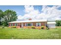 Well-maintained brick home with white metal roof, manicured lawn, and separate two car garage at 765 York Institute Rd, Hiddenite, NC 28636