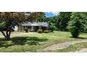 Traditional one-story home featuring a covered entryway, green lawn, and mature trees at 8000 Chapman St, Charlotte, NC 28216