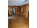 Living room featuring wood paneling, hardwood floors, and an open doorway to the kitchen at 8000 Chapman St, Charlotte, NC 28216