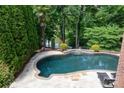 Gorgeous backyard pool and deck surrounded by lush greenery and landscaping offering a private oasis at 132 Parkside Ln, Mooresville, NC 28117