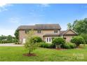Home's rear exterior features a brick facade, well-maintained lawn, and mature trees at 1533 Ohara Plantation Ct, Dallas, NC 28034