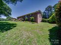 Expansive backyard with lush green grass and mature trees surrounding the brick home at 1830 Huntington Pl, Rock Hill, SC 29732