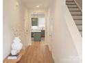 Inviting hallway with hardwood floors leading to a kitchen with gray cabinets and a kitchen island at 320 Lawrence Gray Rd, Charlotte, NC 28262